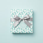Square gift wrapped in balloon-patterned birthday wrapping paper with a silver satin ribbon and matching gift tag.