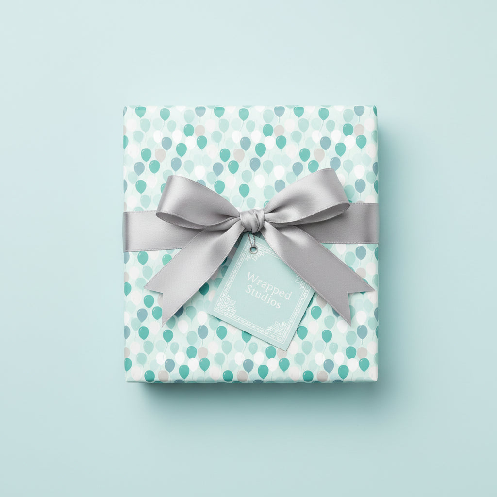 Square gift wrapped in balloon-patterned birthday wrapping paper with a silver satin ribbon and matching gift tag.
