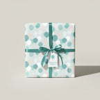 Square gift wrapped in balloon-patterned birthday wrapping paper with a teal ribbon.
