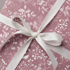 Mauve floral wrapping paper with white ribbon bow, elegant birthday gift wrap.