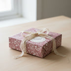 Elegant gift wrapped in mauve floral wrapping paper with a lace ribbon.