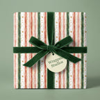 Striped Christmas wrapping paper with a dark green velvet ribbon and gold dots from Wrapped Studios.
