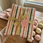 Striped Christmas wrapping paper with a gold ribbon and "For you, Sis" tag.