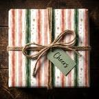 Striped gift wrapped in modern Christmas wrapping paper, tied with jute and a "Cheers" tag.