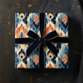Modern ikat pattern wrapping paper in blue, orange, and cream, tied with a luxurious navy velvet ribbon, perfect for any special occasion.