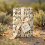 Southwest cactus wrapping paper with a cream satin bow in a desert setting by Wrapped Studios.