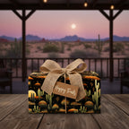 Rustic "Happy Trails" gift with cactus wrapping paper and burlap bow, against a desert scene.