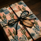 Southwest cactus wrapping paper on a gift box with a black twine bow and wooden tag by Wrapped Studios.