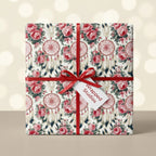 Boho floral and dreamcatcher wrapping paper by Wrapped Studios, tied with a red ribbon on a gift box.