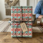 Boho southwestern wrapping paper in turquoise and rust, tied with a brown leather cord by Wrapped Studios.