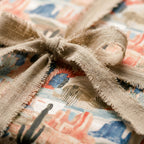 Southwest desert wrapping paper with cacti, tied with a frayed linen bow. Boho gift wrap by Wrapped Studios.