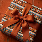 Southwestern wrapping paper with Aztec print and a rust orange ribbon bow by Wrapped Studios.