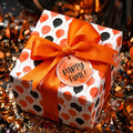 Orange and black balloon birthday wrapping paper with satin bow and Party Time tag by Wrapped Studios.