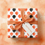 Orange and black watercolor balloon birthday wrapping paper with a matching bow and tag by Wrapped Studios.