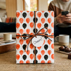 Orange and black balloon birthday wrapping paper by Wrapped Studios with a Cheers tag and twine bow.