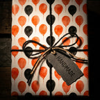 Orange and black balloon Halloween wrapping paper with twine bow, by Wrapped Studios.