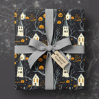 Gift wrapped in Halloween wrapping paper with pumpkin and haunted house pattern and grey ribbon.