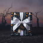 Spooky Halloween gift wrap with pumpkins and haunted houses, finished with a satin white ribbon and tag.