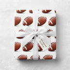 Football wrapping paper by Wrapped Studios. Gift with a white ribbon and bow.