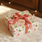 Elegant square gift wrapped in floral wrapping paper with coral ribbon and bow.