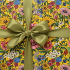 Bright yellow floral wrapping paper with olive green ribbon, perfect for birthday gifts or special occasions.