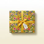 Gift wrapped in vibrant yellow floral wrapping paper with matching satin bow and a tag.