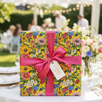 Bright floral wrapping paper with a pink ribbon on a gift at an outdoor party.