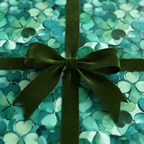 Close-up of a gift wrapped in green floral wrapping paper with a dark green velvet ribbon.