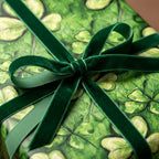 Elegant gift wrapped in lucky clover print wrapping paper with a dark green velvet bow.