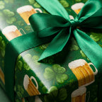 St. Patrick's Day wrapping paper with beer mugs and shamrocks, tied with a green satin bow by Wrapped Studios.