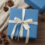 Solid blue wrapping paper on a square gift box with cream ribbon, tag, and pinecone accents, perfect for elegant Christmas presents.