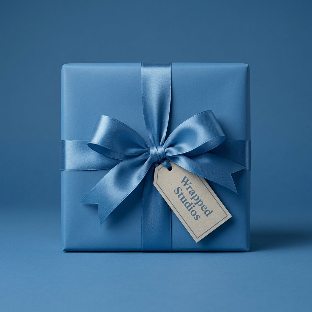 Square gift wrapped in solid blue paper with matching satin ribbon and bow, tag attached.