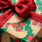 Strawberry and banana fruit wrapping paper with a red satin ribbon bow by Wrapped Studios.