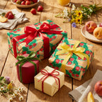 Strawberry and banana fruit wrapping paper on gift boxes on a summer picnic table by Wrapped Studios.