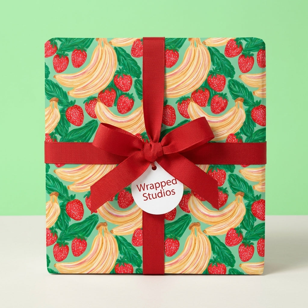 Playful strawberry wrapping paper with bananas and a red ribbon bow by Wrapped Studios.