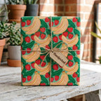 Playful strawberry and banana fruit wrapping paper on a gift box tied with twine by Wrapped Studios.
