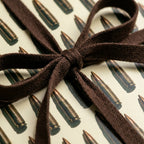 Bullet pattern wrapping paper tied with a brown ribbon bow, masculine gift wrap by Wrapped Studios.