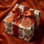 Luxury botanical wrapping paper with moths and eyes, tied with a rust satin bow. By Wrapped Studios.