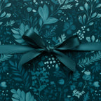 Elegant gift wrapped in dark teal floral wrapping paper with a matching satin ribbon bow.