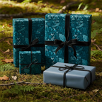 Elegant gifts wrapped in teal floral wrapping paper with black velvet ribbons, styled in a woodland setting.