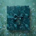 Teal square gift box wrapped in floral wrapping paper with satin ribbon and gift tag.