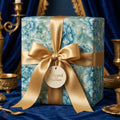 Luxury blue floral wrapping paper with a gold satin bow and gift tag by Wrapped Studios.