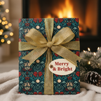 Elegant Christmas gift wrapped in dark floral paper with red and green accents, a gold glitter ribbon, and a "Merry & Bright" tag.