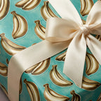 Quirky banana wrapping paper with cream satin ribbon, unique birthday gift wrap by Wrapped Studios.