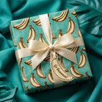 Playful teal banana wrapping paper with a cream ribbon and gift tag by Wrapped Studios.