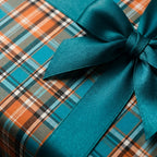 Teal and orange plaid wrapping paper with a matching satin ribbon bow, perfect for holiday gifts by Wrapped Studios.