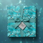 Square gift box wrapped in turquoise stone-patterned paper with matching bow.
