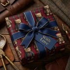 Vintage teddy bear Christmas wrapping paper on red tartan gift box with navy bow by Wrapped Studios.
