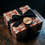 Vintage teddy bear Christmas wrapping paper on a gift box with a black bow and Noel tag by Wrapped Studios.