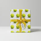 Wrapped Studios tennis ball wrapping paper with gold ribbon; unique gift wrap for sports fans.